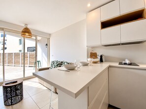 A modern kitchen with a large island, white cabinetry, and a hanging light fixture.