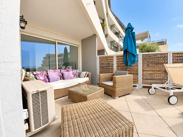 An outdoor patio area with wicker furniture, a seating arrangement, and a view of the sky.