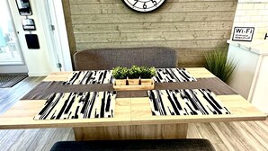 Una mesa de comedor con camino de mesa estampado de cebra, un reloj en la pared y un banco adelante.