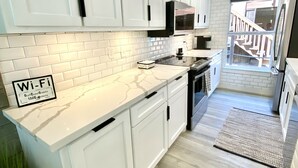 Una cocina moderna con armarios blancos, encimera de mármol y un cartel de Wi-Fi que indica servicios para huéspedes.
