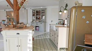 Una cocina con armarios blancos, una isla central y un refrigerador antiguo.