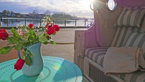 Un patio con una zona de estar, un jarrón con flores y vistas a un lago.
