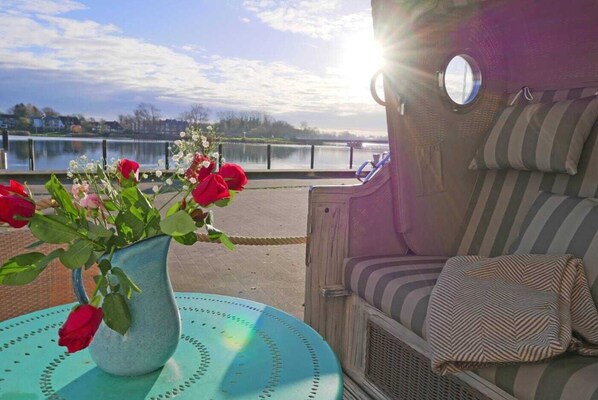 Un espace patio aménagé avec des sièges, un vase de fleurs et une vue sur un lac.