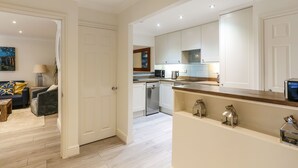 Une cuisine moderne avec des meubles blancs, un lave-vaisselle et un plan de travail en bois.