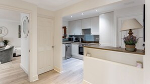 Une cuisine moderne avec des meubles blancs, un plan de travail et un four encastré.