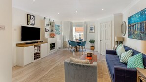 Un salon moderne doté d’un téléviseur à écran plat, d’un canapé, d’un coin repas avec des chaises et d’une cheminée.