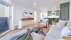Een moderne woonkamer met een bank, een salontafel en een eethoek, met een keuken op de achtergrond.