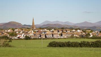 A town with a prominent church tower, houses, and rolling hills in the background.