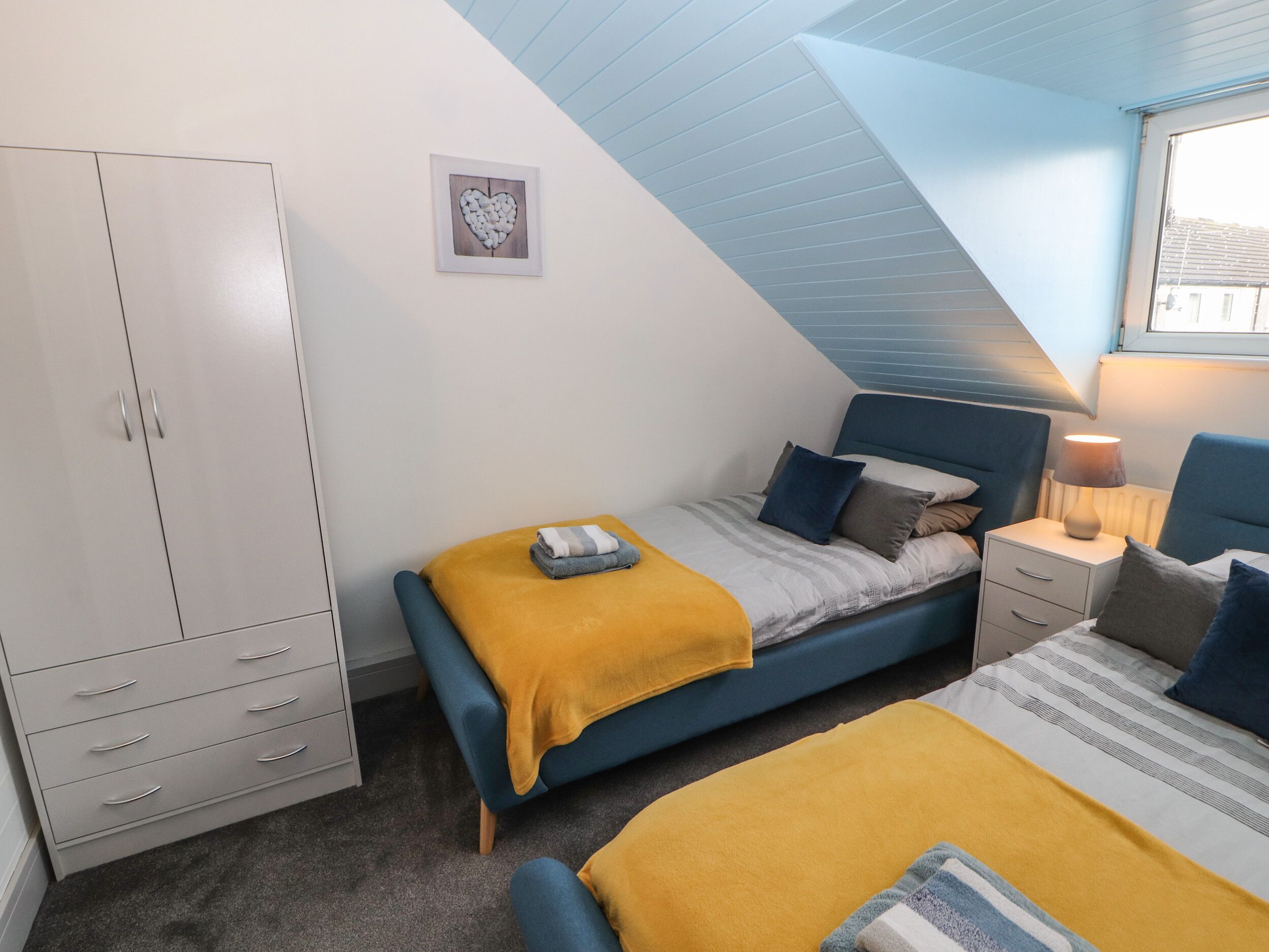 Quarto com cama, mesa de cabeceira, luminária e guarda-roupa.