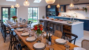 A modern kitchen with dark blue cabinets, a white island, and pendant lighting. - Bennar Fawr (Dyffryn Ardudwy)