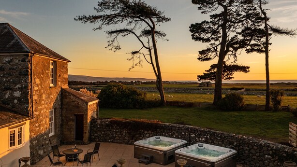 A stone building with a patio, outdoor seating, and hot tubs. - Bennar Fawr (Dyffryn Ardudwy)