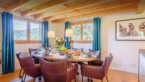 A dining area with a round table set for six, surrounded by leather chairs with wheels. - Chalet Joux Verte - beautiful ski base for 8 with spa - OVO Network (Les Gets)