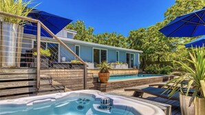 Ein Garten mit Whirlpool, Schwimmbecken und einer überdachten Terrasse.