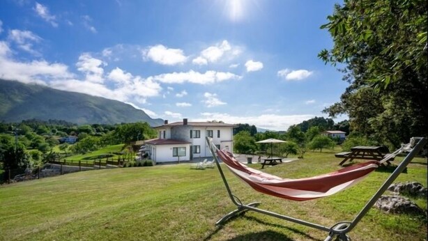 A hammock in a grassy area with a house in the background. - La Rexidora - Bisonte apt. in Cuerres (Ribadesella) | 2–4 guests (Cuerres (Ribadesella))