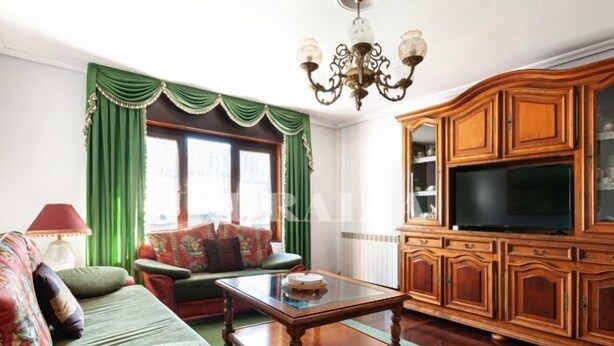 Una sala de estar con un sofá, una mesa de centro, un televisor y armarios de madera.