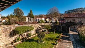 Un patio con muros de piedra, una pérgola de madera y un puente de piedra.