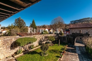 A courtyard with stone walls, a wooden pergola, and a stone bridge. - Casa Paco - country house with garden in Caranceja (Reocín, Cantabria) (Caranceja)
