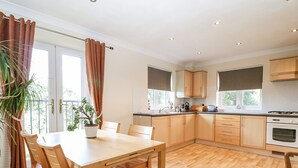 Een moderne keuken met houten kastjes, een eettafel en stoelen.