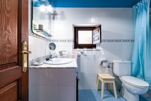 A bathroom with a wooden door, a sink, a toilet, and a small stool. - Casa Begoña - country house with mountain views near Ribadesella (Sardedo)