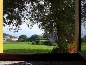 A window view of a green landscape with a building in the distance. - Apto Tapia 1 - rural apartment in Luces (Colunga), Northern Spain (Luces)