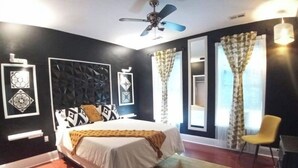 Un dormitorio moderno con una cama, un ventilador de techo y una ventana con cortinas.