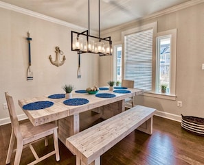 A dining area with a wooden table, blue placemats, and a hanging light fixture.