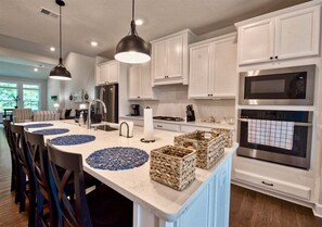 A modern kitchen with white cabinets, a central island with blue placemats, and stainless steel appliances.