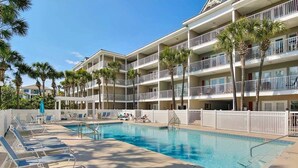 Un hotel amb zona de piscina, diversos balcons i palmeres.