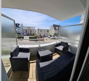 A balcony with outdoor seating, a view of buildings, and a clear sky. - Studio beach pornichet (Pornichet)