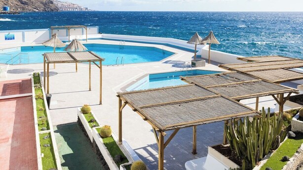 A pool area with a view of the sea, including a pool, sun loungers, and a cactus garden. - Home2Book Relax Caletillas, Terrace & Pool (Las Caletillas)