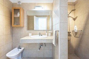 Une salle de bain moderne équipée d’un lavabo, d’un bidet, d’un miroir et d’une douche.