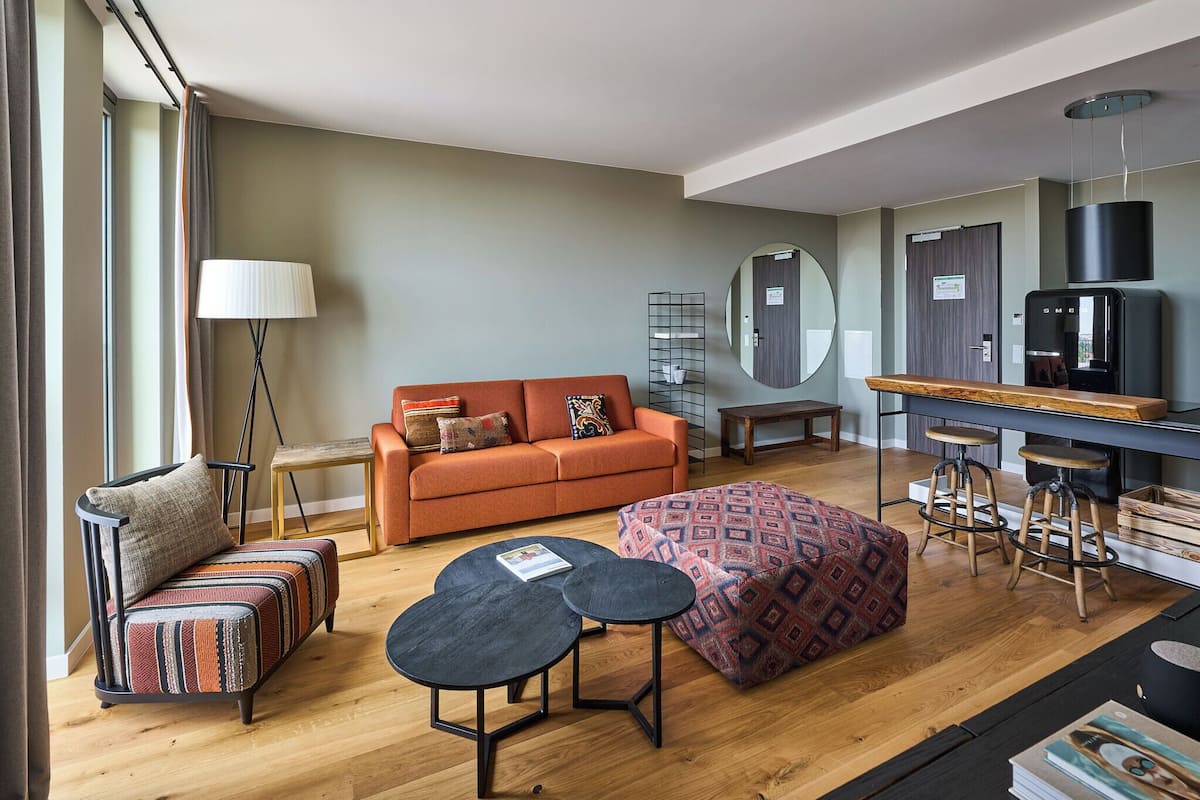 A modern living room with a sofa, ottoman, coffee table, and bar stools.