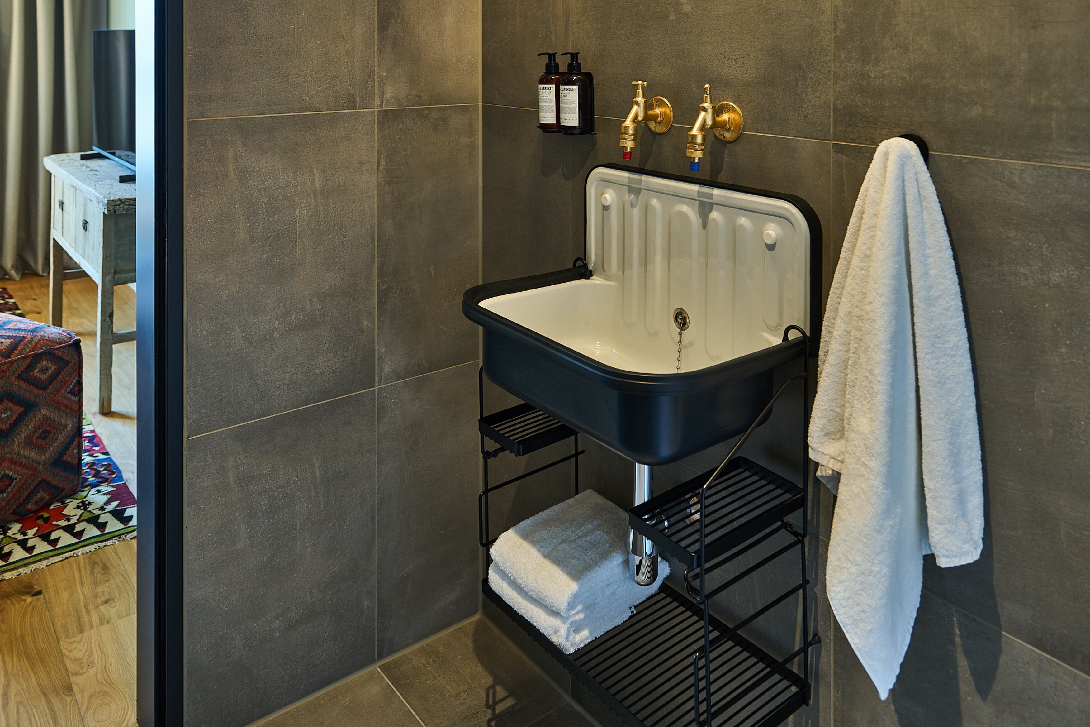 Ein Badezimmer mit einem schwarz-weißen Waschbecken, einem Handtuchhalter und einem Ablagefach mit Toilettenartikeln.