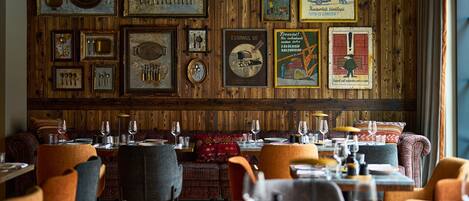 A restaurant with wooden panel walls, vintage posters, and a variety of seating options including tables and booths.