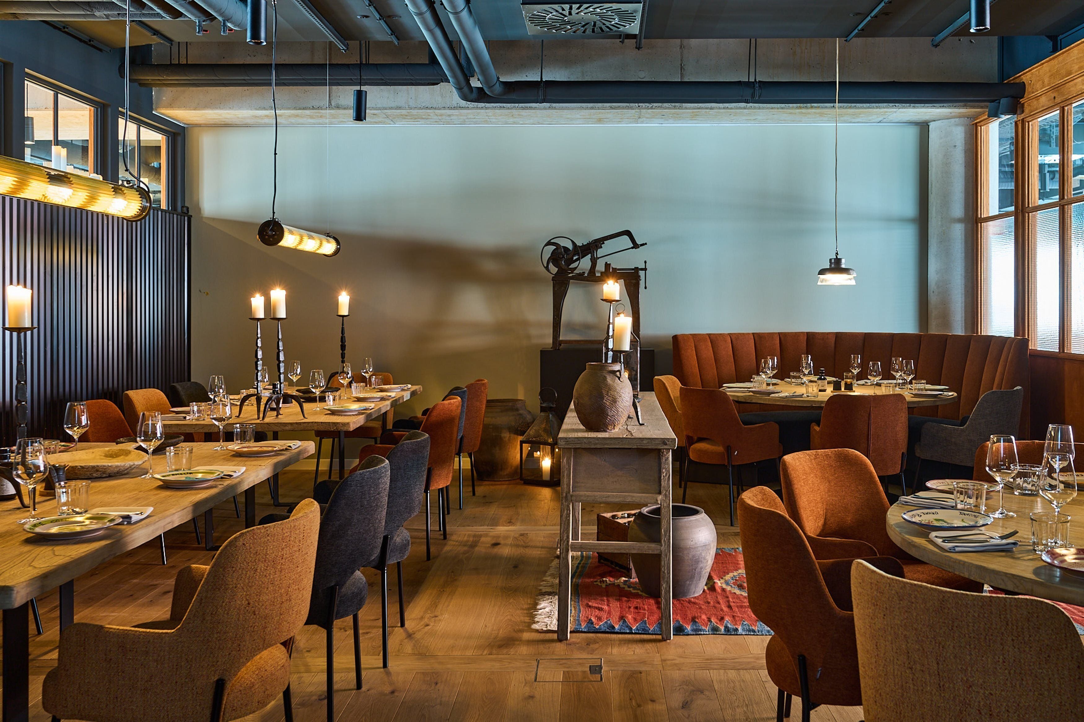 A restaurant with long tables, candles, and a rustic decor.