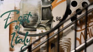 Un mur orné d’une fresque représentant des ustensiles de cuisine, avec l’inscription « Fast Food Italy ».