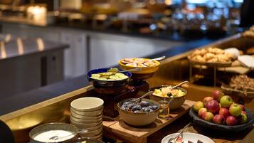 A buffet with various fruits, bowls of yogurt, and a selection of cheeses.