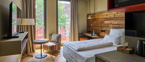A hotel room with a bed, desk, chair, TV, and a view of the outdoors.