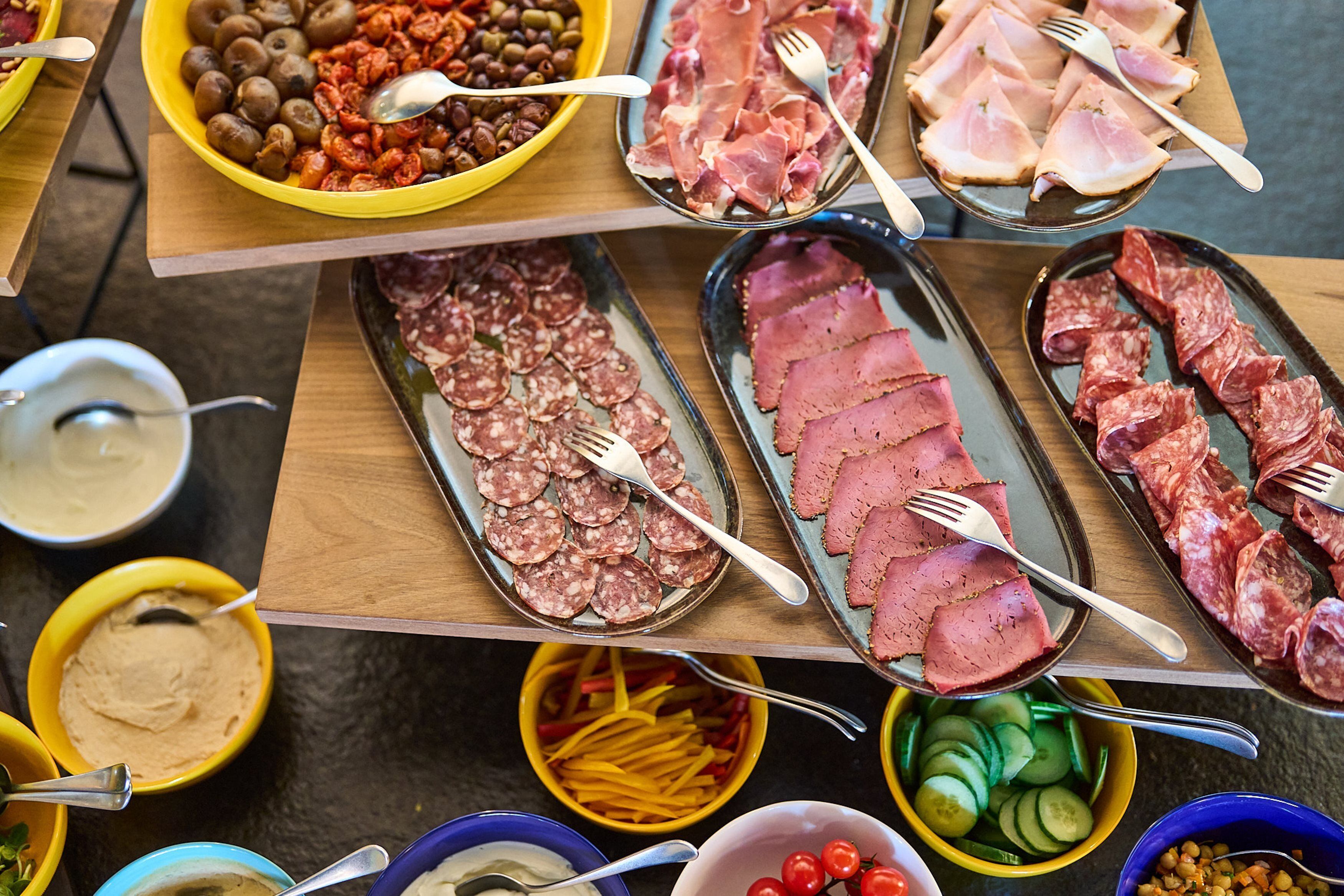 A buffet table with various food items including meats, cheeses, and vegetables.
