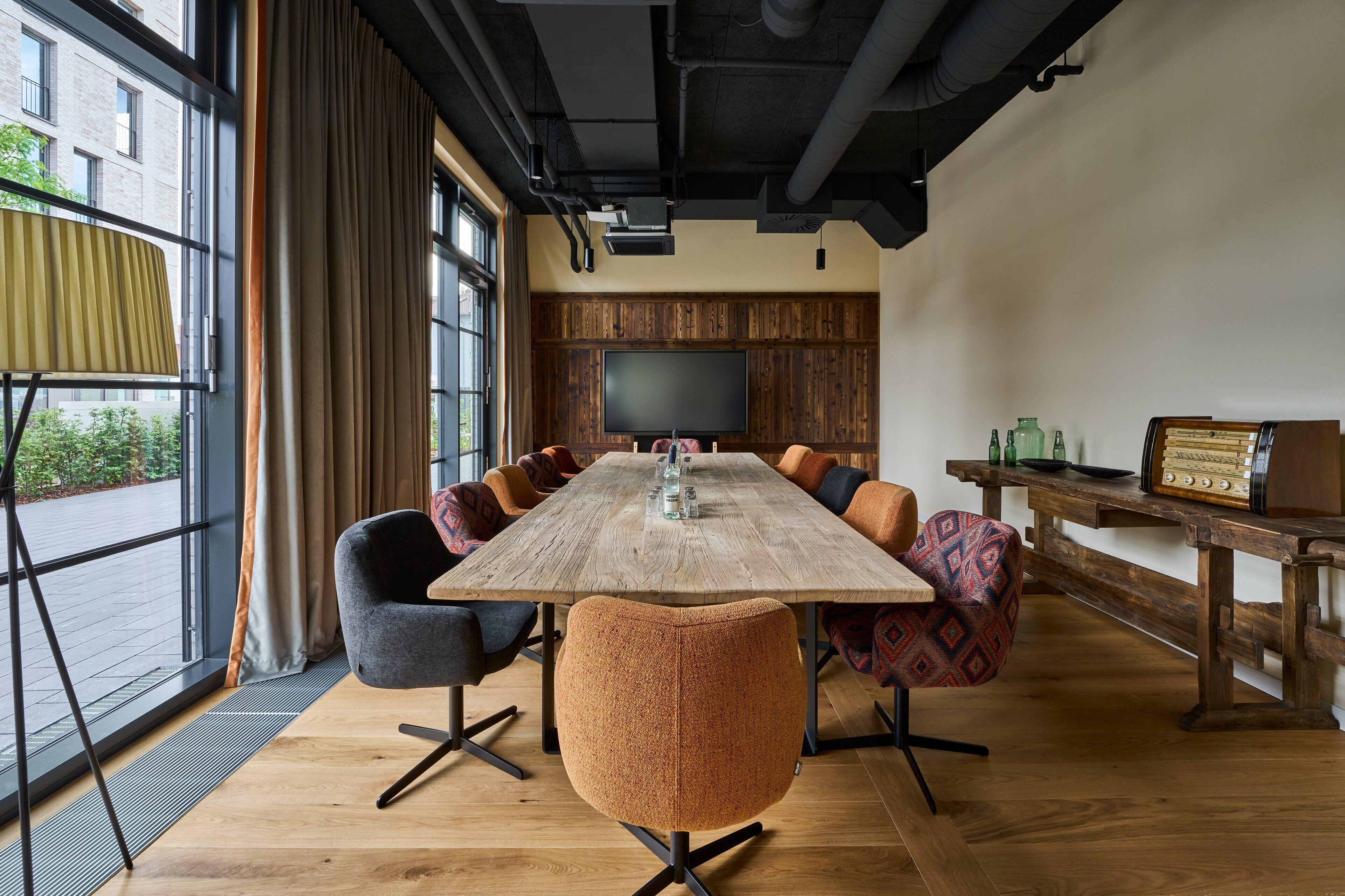 A conference room with a long table, multiple chairs, a television, and a wooden panel wall.
