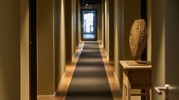 A long, narrow hallway with a wooden floor and a central light source at the end.