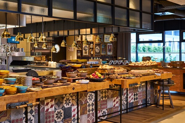 A kitchen with a long counter, various cooking utensils, and hanging lights. - FREIgeist Göttingen Nordstadt - A Member of Design Hotels™ (Goettingen)