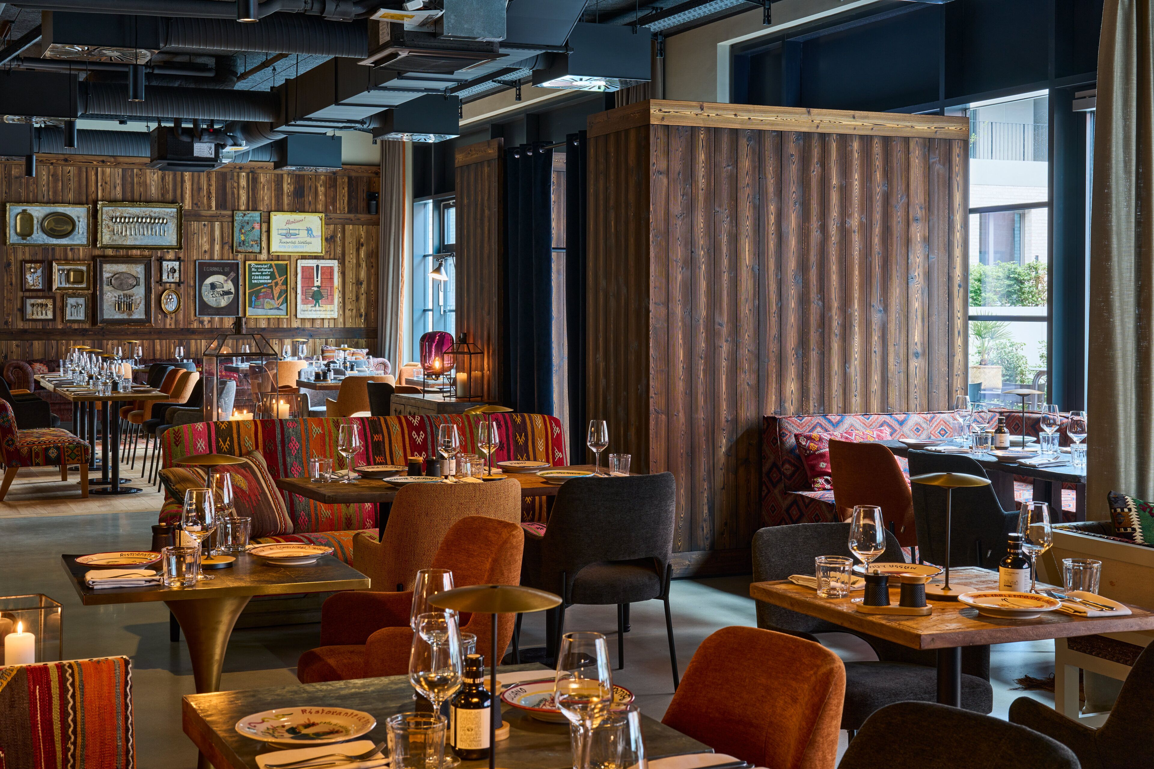A restaurant with wooden walls, tables set with wine glasses, and a variety of seating options.