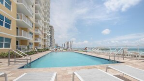 Ein Swimmingpool mit Liegestühlen und Blick auf ein Hochhaus.