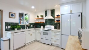 A modern kitchen with white cabinets, a stainless steel dishwasher, a white stove, and a built-in oven. - Modern A-Frame next to a creek, minutes to Bass Lake and close to Yosemite  (Oakhurst)