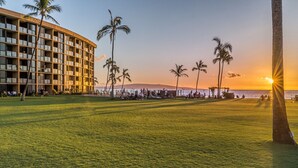 A hotel with a pool area, palm trees, and a sunset view. - Enjoy Your Oceanside Dream at Kihei Surfside (Kihei)