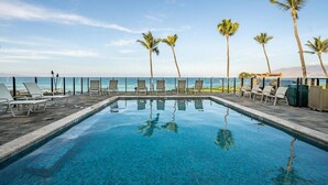 A poolside area with lounge chairs and palm trees, overlooking a body of water. - Enjoy Your Oceanside Dream at Kihei Surfside (Kihei)