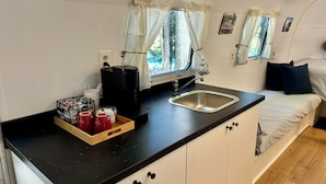 Una kitchenette compacta con cafetera, lavamanos y alacenas.