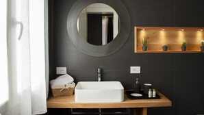 A modern bathroom with a rectangular sink, a round mirror, and a shelf with potted plants. - Two bedroom apartment with ensuite bathrooms in a perfect location. (Venezia)