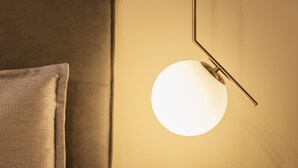 A modern room with a round wall light fixture and a brown headboard. - Two bedroom apartment with ensuite bathrooms in a perfect location. (Venezia)